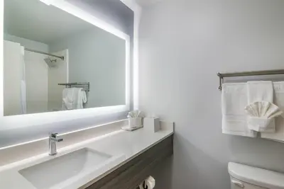 a white bathroom with a sink and a mirror at Hourglass Hotel, Trademark Collection by Wyndham in Bakersfield