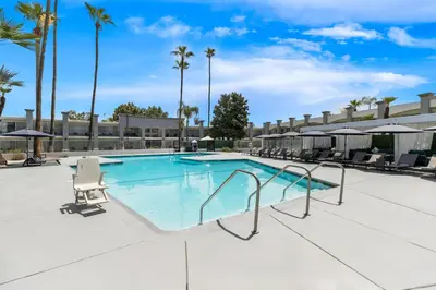 a swimming pool at a resort with chairs and palm trees at Hourglass Hotel, Trademark Collection by Wyndham in Bakersfield