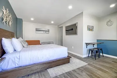 a bedroom with a bed and a table and a desk at White Caps Motel in Ventura