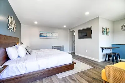 a bedroom with a bed and a table and a desk at White Caps Motel in Ventura