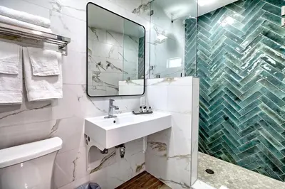 a white bathroom with a sink and a mirror at White Caps Motel in Ventura