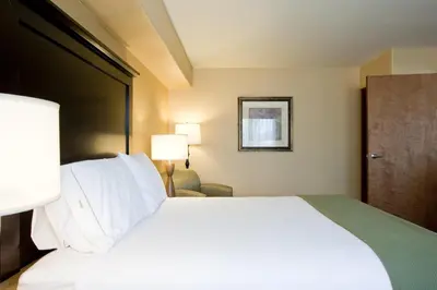 a hotel room with a large bed with white pillows at Holiday Inn Express & Suites Woodland Hills by IHG in Woodland Hills