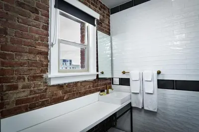 a bathroom with two sinks and a brick wall at H by H Hospitality in Los Angeles