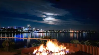 a fire pit in front of the water at night at Hotel Maya in Long Beach