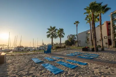 a sandy beach with blue towels and palm trees at Hotel Maya in Long Beach