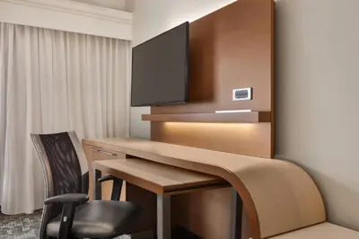 a room with a desk with a television on a wall at Courtyard by Marriott Palmdale in Palmdale