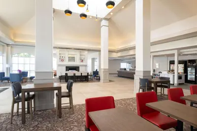 a dining room with tables and chairs and a fireplace at Hilton Garden Inn Fontana in Fontana