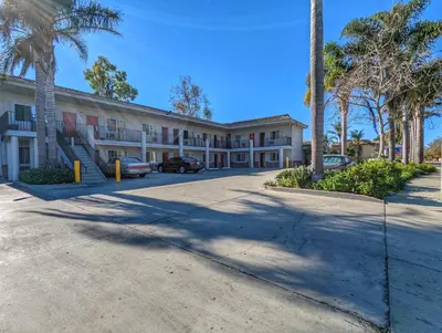 a large building with palm trees in front of it at Americas Best Value Inn Oxnard-Port Hueneme in Port Hueneme
