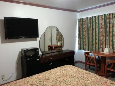 a bedroom with a bed and a mirror and a table at Walls Motel Long Beach in Long Beach