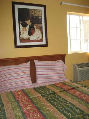 a bed with two pillows and a picture on the wall at Walls Motel Long Beach in Long Beach