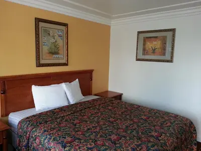 a hotel room with a bed and two pictures on the wall at Tower Motel Long Beach in Long Beach