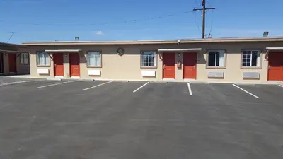 a building with red doors in a parking lot at Motel 6 Maple/Main in Hesperia