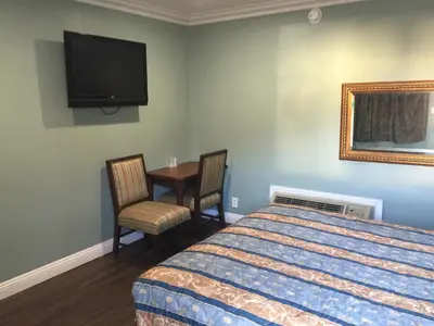 a bedroom with a bed and a table and a tv at Park Motel in Los Angeles