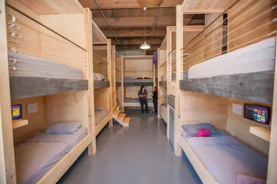 a room with four bunk beds and a person standing in it at PodShare DTLA in Los Angeles