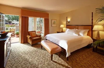 a bedroom with a bed and a chair and a window at The Mission Inn Hotel and Spa in Riverside