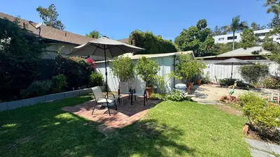 a backyard with a table and an umbrella at Dresden B & B in Los Angeles