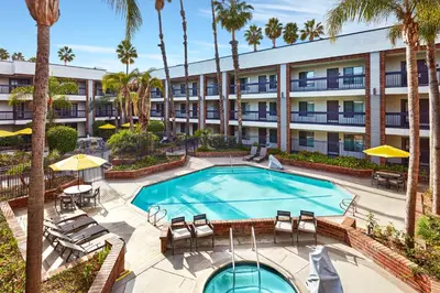 an apartment building with a pool and palm trees at Best Western Plus Meridian Inn & Suites, Anaheim-Orange in Orange