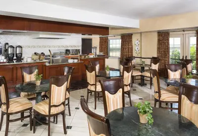 a restaurant with tables and chairs and a kitchen at Ayres Suites Ontario at the Mills Mall - Rancho Cucamonga in Ontario
