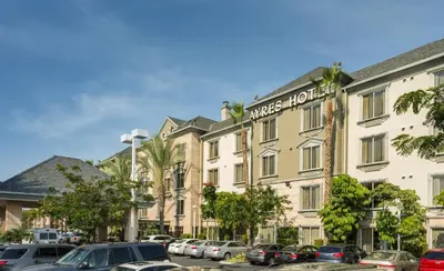 a building with cars parked in a parking lot at Ayres Hotel Anaheim in Anaheim