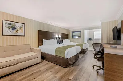 a hotel room with two beds and a couch at Quality Inn & Suites Anaheim Maingate in Anaheim