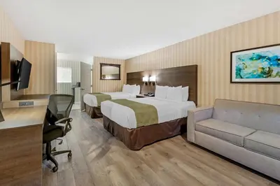 a hotel room with two beds and a couch at Quality Inn & Suites Anaheim Maingate in Anaheim