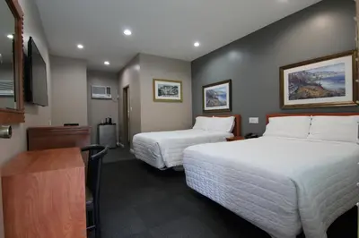 a hotel room with two beds and a desk at Dunes Inn - Wilshire in Los Angeles