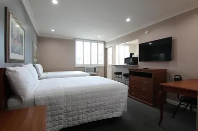 a bedroom with a bed and a desk and a television at Dunes Inn - Wilshire in Los Angeles
