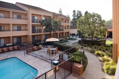 an exterior view of a hotel with a pool and tables and chairs at Sonesta Select Los Angeles LAX El Segundo in El Segundo
