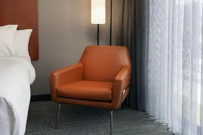 an orange chair sitting next to a bed in a hotel room at Courtyard by Marriott Los Angeles Hacienda Heights Orange County in Hacienda Heights