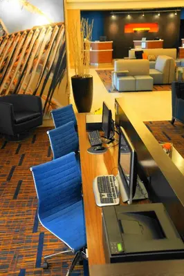 an office with a desk with a computer and blue chairs at Courtyard by Marriott Baldwin Park in Baldwin Park