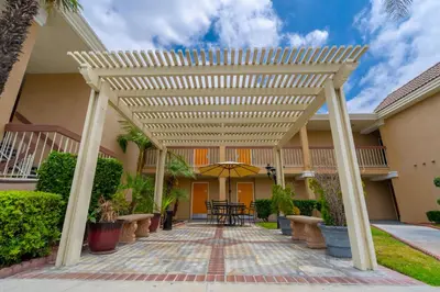 a wooden pergola in the courtyard of a house at Howard Johnson by Wyndham Buena Park in Buena Park