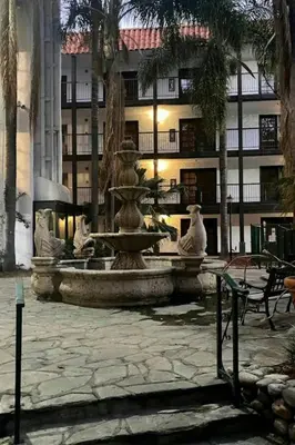 a fountain in the middle of a courtyard with a building at The Buena Park Grand Hotel & Suites in Buena Park