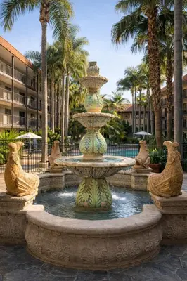 a large fountain in a courtyard with palm trees at The Buena Park Grand Hotel & Suites in Buena Park
