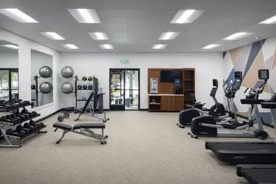 a gym with several treadmills and machines in a room at The Buena Park Grand Hotel & Suites in Buena Park