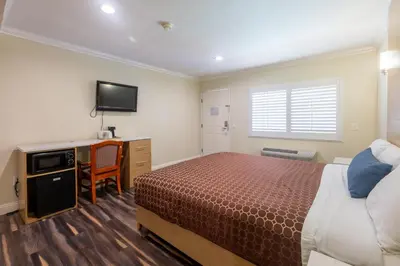 a bedroom with a bed and a desk and a television at Hollywood City Inn in Los Angeles