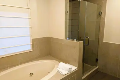 a bathroom with a tub and a glass shower at Ramada by Wyndham Culver City in Los Angeles