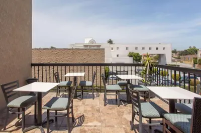 a patio with tables and chairs on a balcony at Ramada by Wyndham Culver City in Los Angeles