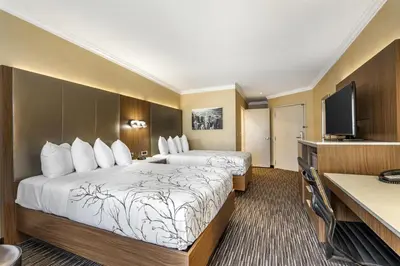 a hotel room with two beds and a flat screen tv at Best Western Airpark Hotel - LAX Airport LA Stadium in Inglewood