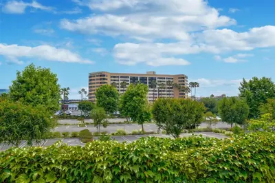 a building in a parking lot with trees at Embassy Suites by Hilton Anaheim-Orange in Anaheim