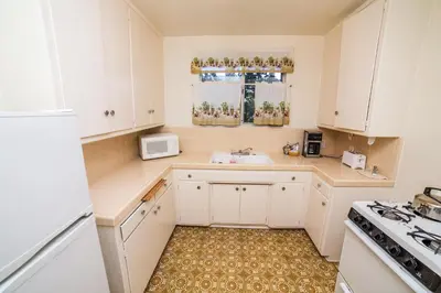 a kitchen with white cabinets and a sink at Cal Mar Hotel Suites in Los Angeles