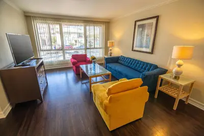 a living room with a blue couch and red chairs at Cal Mar Hotel Suites in Los Angeles