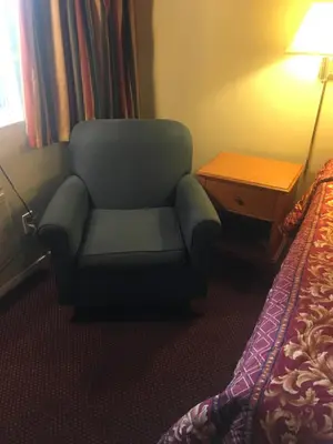 a chair sitting next to a bed in a hotel room at Century Inn at LAX in Inglewood