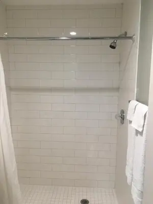 a bathroom with a white tiled shower with towels at Century Inn at LAX in Inglewood