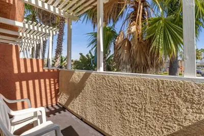 a pair of white chairs sitting on a porch with palm trees at Comfort Inn & Suites Huntington Beach in Huntington Beach