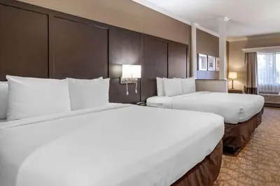 a hotel room with two beds with white sheets at Comfort Inn & Suites Huntington Beach in Huntington Beach