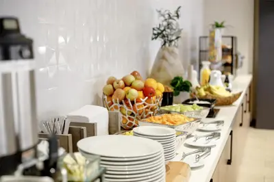 a table with plates and bowls of fruit on it at Hilton Garden Inn LAX Los Angeles Airport in Los Angeles