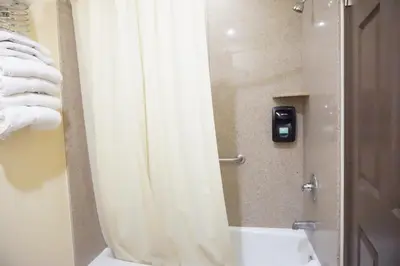 a bathroom with a shower with a white shower curtain at Tuscan Garden Inn in Los Angeles