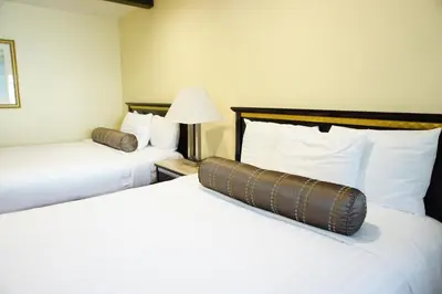 a hotel room with two beds with white sheets at Tuscan Garden Inn in Los Angeles