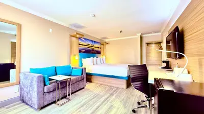 a hotel room with a bed and a couch and a desk at Days Inn by Wyndham Los Angeles LAX South Bay Beach City LA in Lawndale