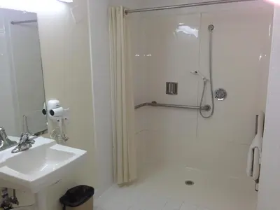 a white bathroom with a shower and a sink at Jolly Roger Hotel in Los Angeles